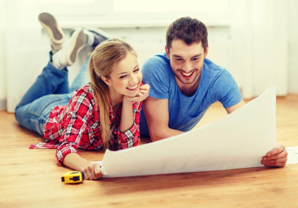 smiling couple looking at blueprint at home