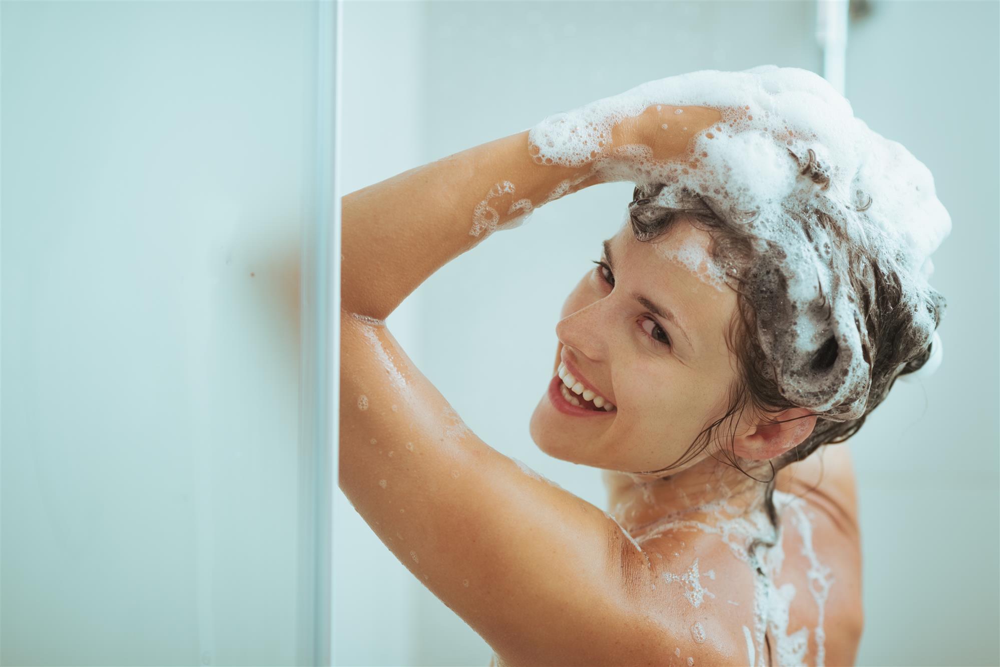 Woman washing hair in shower.