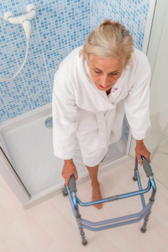 Elderly woman going out of the shower with his walker.