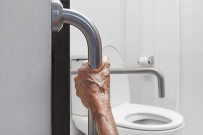 Elderly man holding on handrail in bathroom