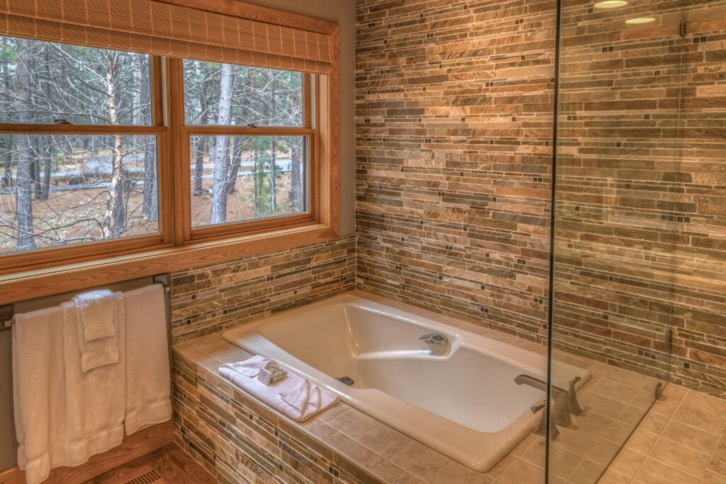 Bathtub with stone walls and view to the woods