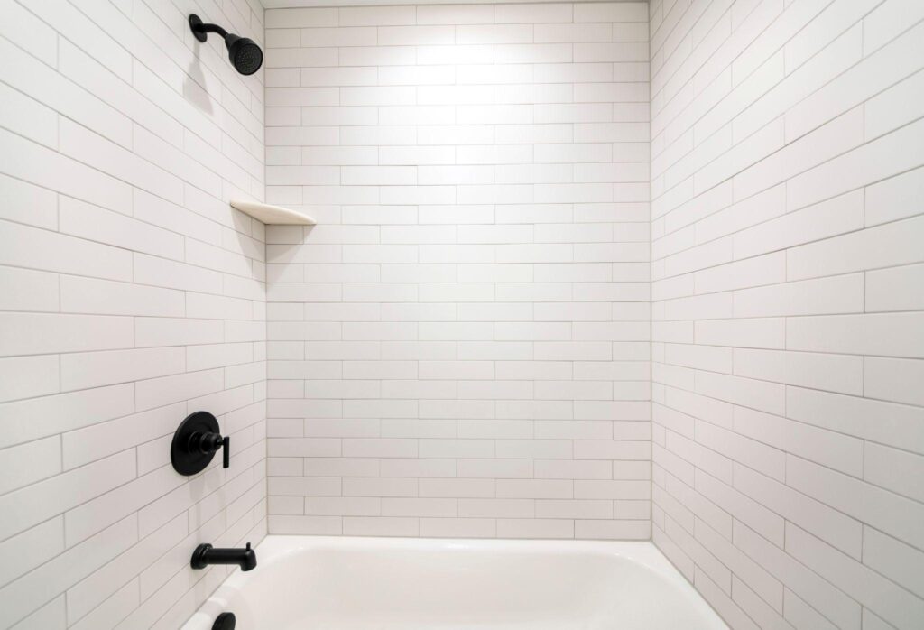 Alcove bathtub with black plumbing fixtures and white subway tiles wall surround