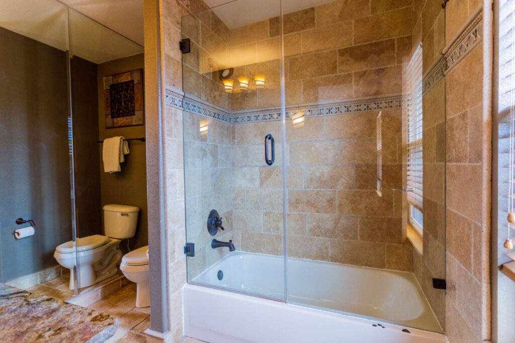 Custom contemporary modern bathroom with tile work, glass tub enclosure, and mirrors