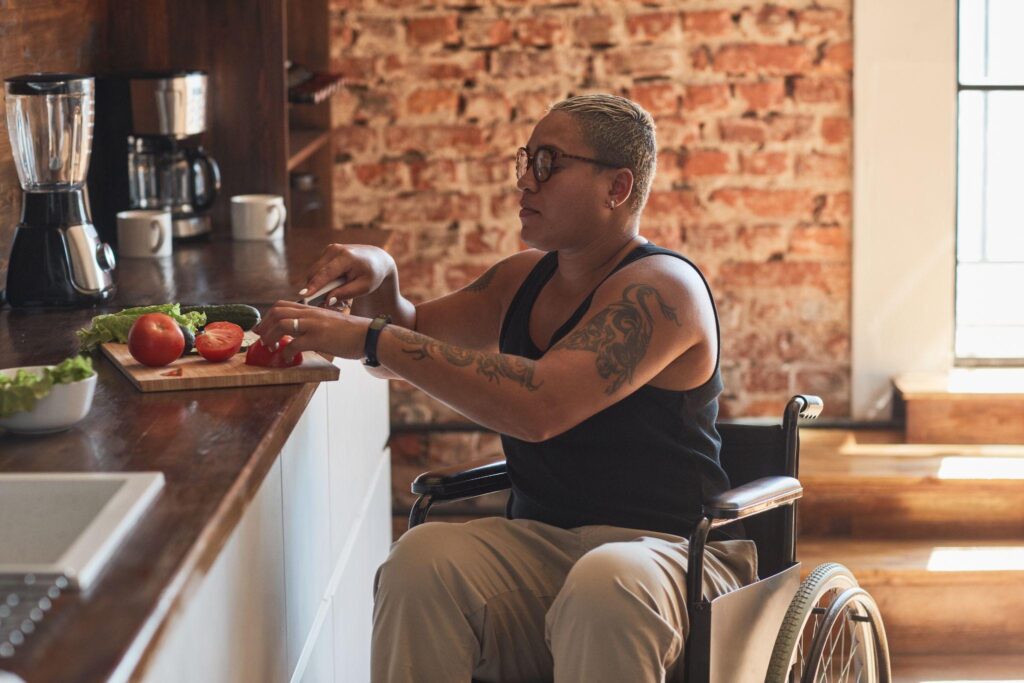 contemporary tattooed woman with disability cooking dinner at home