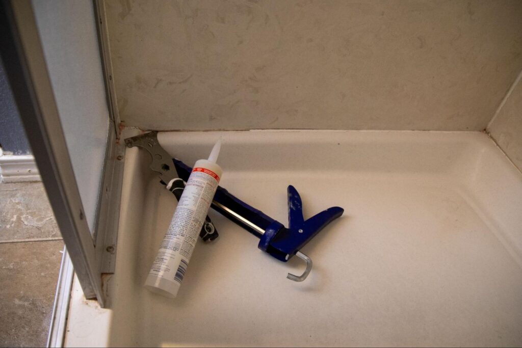Tools to re-caulk a bathroom shower with peeling grout and missing tile.
