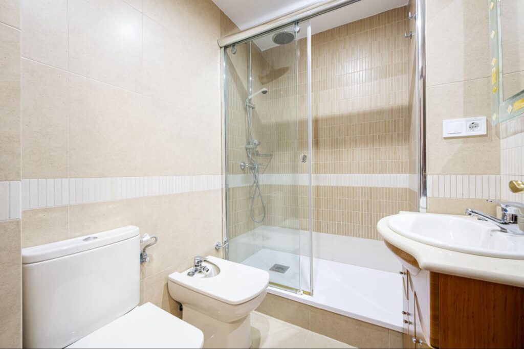 Bathroom with washbasin cabinet with wooden drawers, white marble countertop, square mirror with glass frame and shower cabin with white resin shower.
