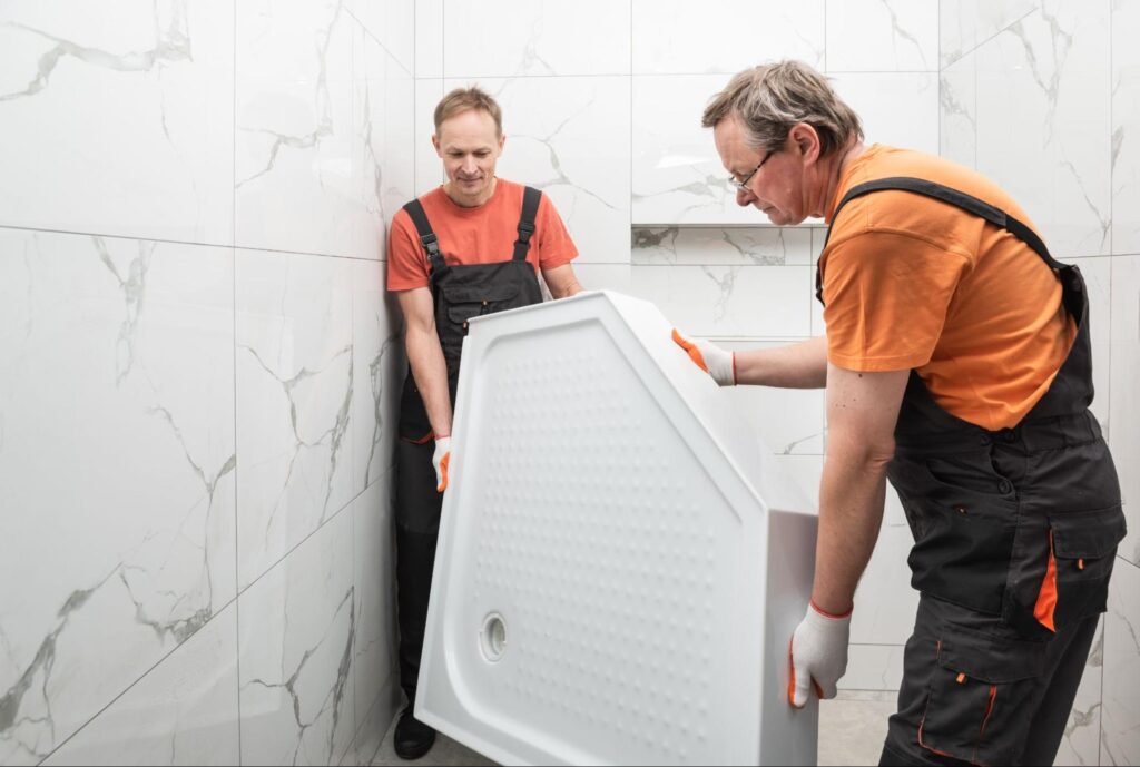 Workers are installing a shower tray in the bathroom.