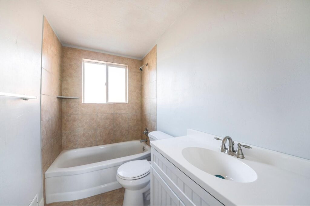 Interior of a bathroom with window on top of a bathtub.