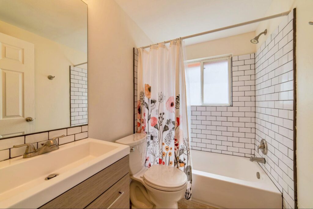 Toilet vanity and built in bathtub with floral shower curtain inside bathroom.