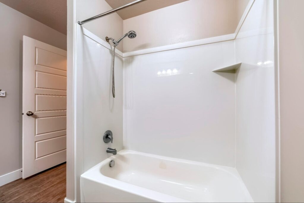 Bathroom interior with built in bathtub stainless steel shower head and faucet.