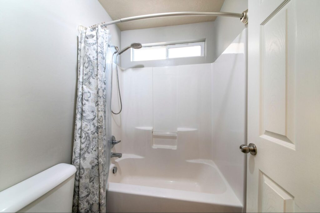 Small bathroom with a white door and a tub shower combo set.